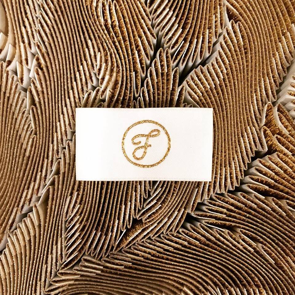 Golden edges of the Figgi label tags in a bunch creating a swirling gold textural base for a Figgi lable tag to sit atop.